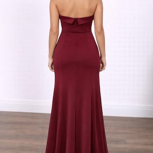 Back view of woman wearing a burgundy strapless Tube Mermaid Maxi Gown on a white background.
