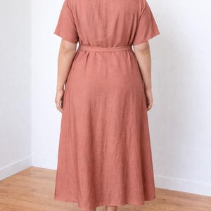 Person wearing a rust-colored Plus Size Kimono Sleeve Maxi Dress standing in a room with wooden flooring and white walls.