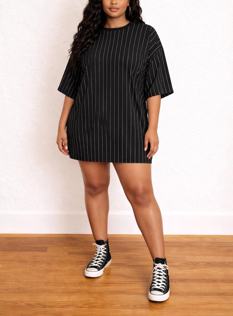 Woman wearing a black pinstripe Plus Size T-Shirt Dress with black high-top sneakers on a wooden floor.