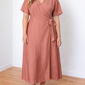 Woman wearing a pink Plus Size Kimono Sleeve Wrap Maxi Dress with a white background.