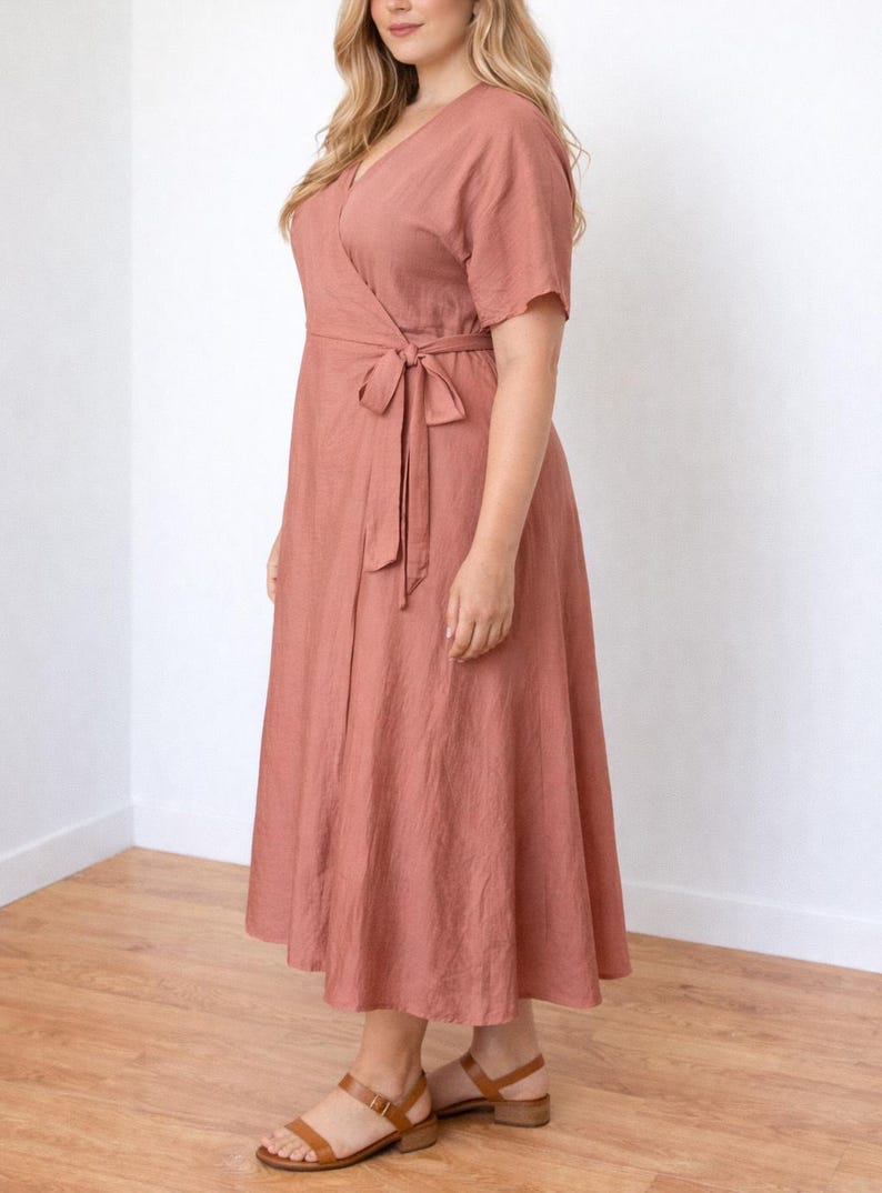 Side view of woman wearing a pink Plus Size Wrap Dress with a white background.