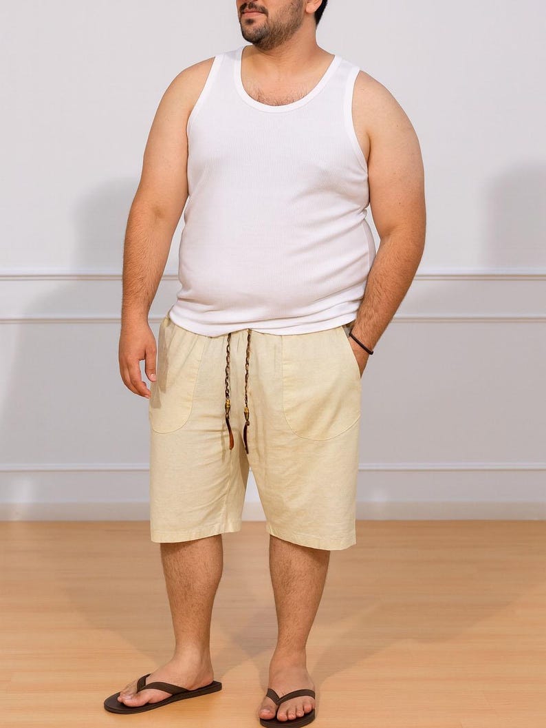 Person wearing white tank top and beige Plus Size Drawstring Knee Length Shorts with plain background and wood flooring.