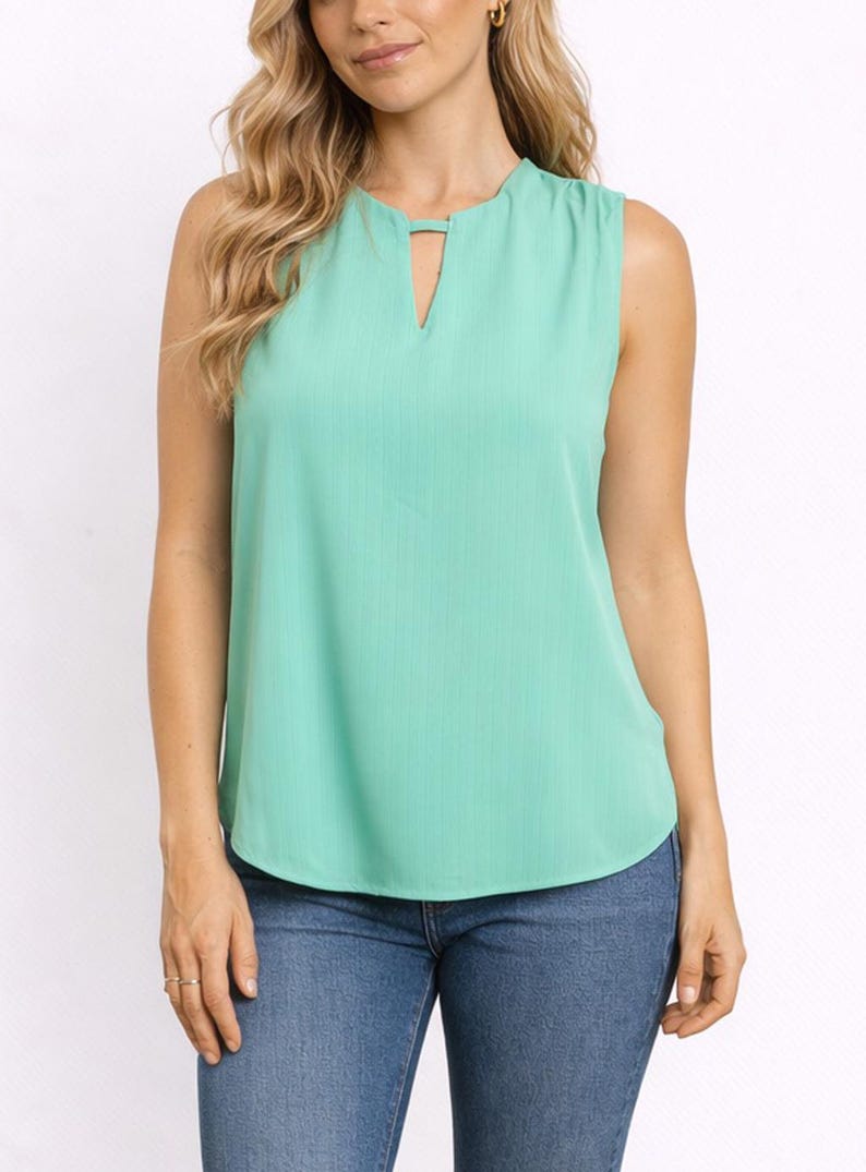 Woman wearing a mint green Keyhole Neckline Sleeveless Top and blue jeans on a white background.