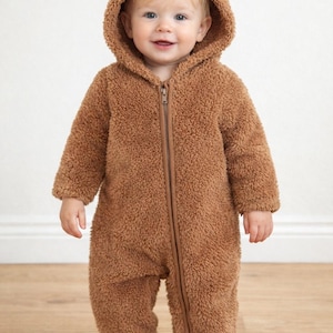Child wearing a brown bear-themed Zipper Front Jumpsuit with a hood against a white background.