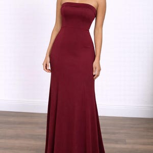 Woman wearing a burgundy strapless Tube Mermaid Maxi Prom Dress on a white background.