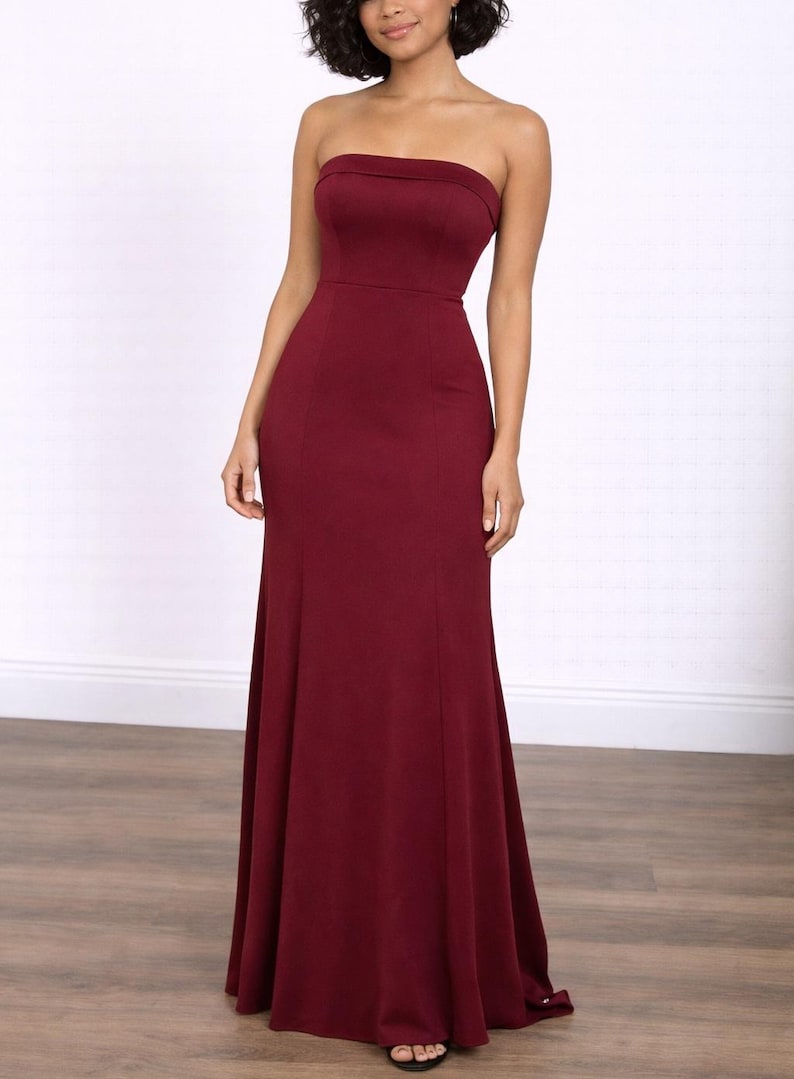 Woman wearing a burgundy strapless Tube Mermaid Maxi Prom Dress on a white background.