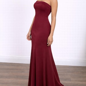 Side view of woman wearing a burgundy strapless Tube Mermaid Maxi Prom Dress on a white background.