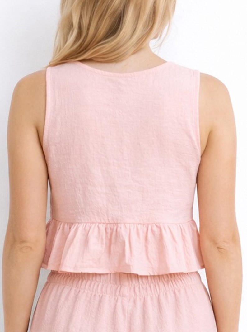 Back view of woman wearing a pink Ruffle Hem Crop Top and pants set on a white background.