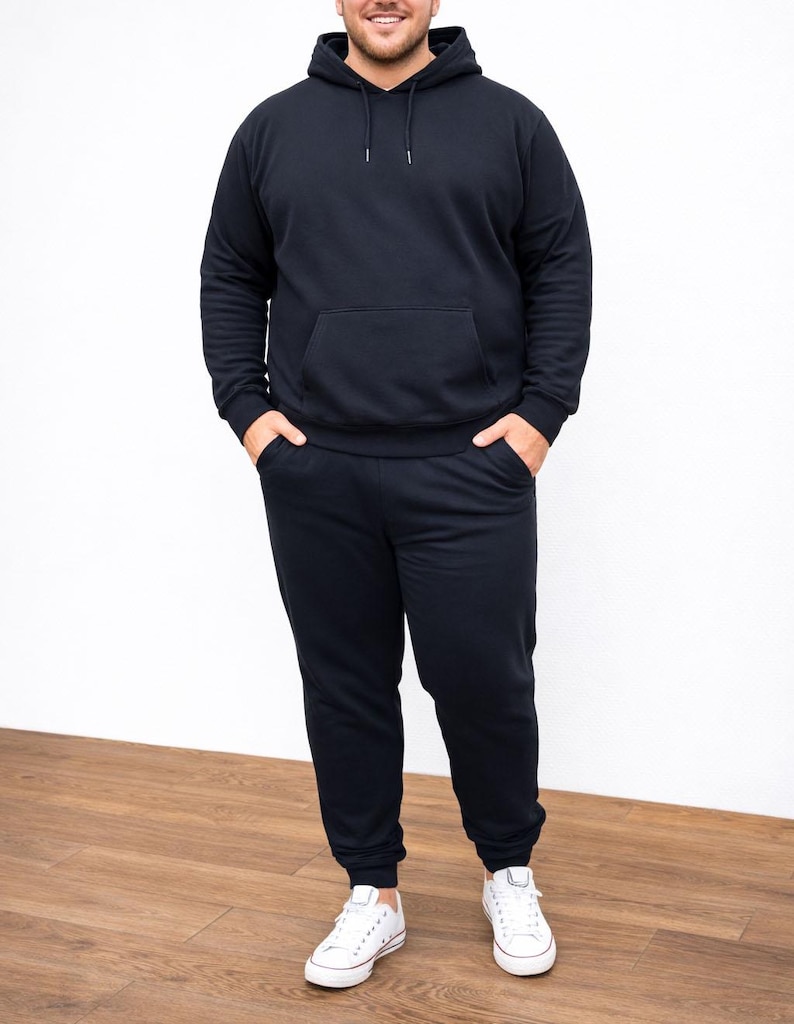 Person wearing a black Plus Size Mens Classic Hoodie and pants with white sneakers on a wooden floor.