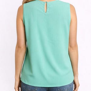 Back view of woman wearing a mint green Keyhole Neckline Sleeveless Top and blue jeans on a white background.
