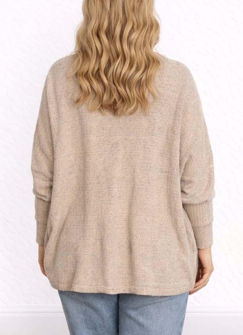 Back view of woman wearing a beige Batwing Sleeve Cardigan and blue jeans on a wooden floor.