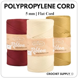 Può includere: Tre bobine di cordino piatto in polipropilene da 5 mm nei colori bordeaux, crema e oro. Ogni bobina presenta un'etichetta di carta color cuoio con il testo STENLI Ribbon e www.stenliyarn.com. In alto appare il testo POLYPROPYLENE CORD 5 mm | Flat Cord.