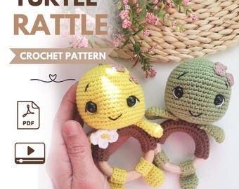 May include: Two crochet turtle rattles featuring yellow and green yarn heads with black safety eyes and small brown wooden rings. The text TURTLE RATTLE CROCHET PATTERN is visible along with a PDF icon and a video play icon on the left side.