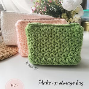 May include: Three crocheted makeup storage bags in white, pink, and green. The bags have a textured, star-like pattern and zippers. The image includes text that says "Make up storage bag + Video tutorials".