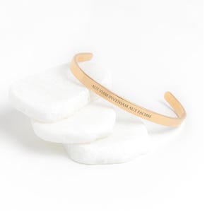 May include: Gold-toned bangle bracelet with the inscription "Aut viam inveniam aut faciam" (I will either find a way or make one).