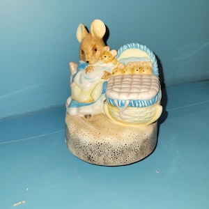 May include: A ceramic figurine of a mother mouse with a baby mouse, and a basket of baby mice. The figurine is painted in pastel colours, with a beige base and a light blue background.