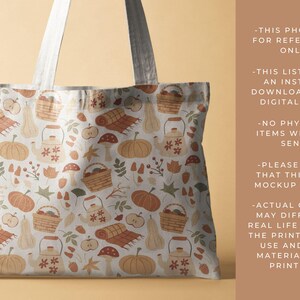 May include: A white tote bag with a fall-themed pattern featuring pumpkins, gourds, leaves, mushrooms, and teapots. The pattern is in shades of orange, brown, and green.