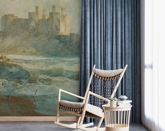 May include: A rocking chair with a woven seat and a wooden frame sits in front of a wall mural depicting a coastal scene with a castle in the distance. The mural is painted in muted tones of blue, green, and brown. A small wooden side table with a potted plant sits next to the chair.