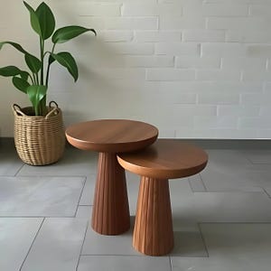Pode incluir: Duas mesas de madeira encaixáveis com um design canelado nas pernas. As mesas são feitas de madeira castanho escura e são uma ótima adição a qualquer sala de estar ou quarto.