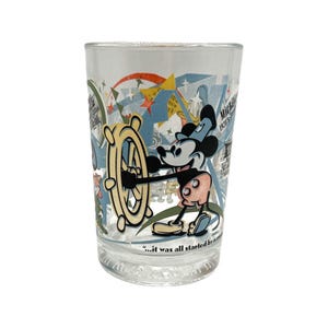 Puede incluir: Vaso transparente con una colorida ilustraci&oacute;n de Mickey Mouse al tim&oacute;n de un tim&oacute;n. El dise&ntilde;o incluye estrellas, texto y una cita. Un vaso coleccionable de estilo vintage.