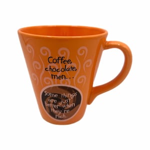 May include: Orange ceramic coffee mug with a curved handle. The mug features white swirl designs and text that reads "Coffee, chocolate, men..." and "Some things are just better when they're rich."