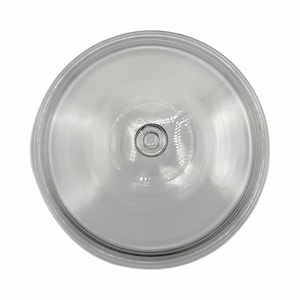 May include: A clear, circular glass lid with a central knob. The lid has a slightly domed shape and a series of concentric rings radiating from the center. The knob is a small, circular indentation.