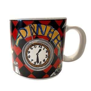 May include: A ceramic coffee mug with a diner theme. The mug features a clock design with the word "DINER" above it. The background has a red and black checkered pattern. The handle is white.