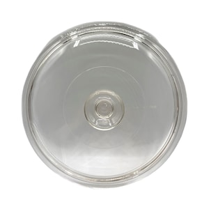 Puede incluir: Una tapa de vidrio transparente y circular con una forma ligeramente abovedada. La tapa tiene un borde elevado y una pequeña hendidura circular en el centro. El vidrio es transparente.