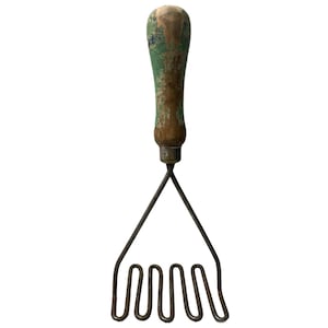 May include: A vintage potato masher with a wooden handle painted green and brown. The metal masher has four prongs.