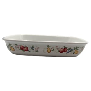 May include: White rectangular ceramic baking dish with a decorative border of red apples, yellow pears, and blue berries. The dish has a gently curved shape.