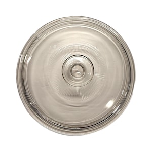 Op de afbeelding: Een heldere, ronde glazen deksel met een centrale knop. De deksel heeft concentrische ringen en een gestructureerd patroon dat vanuit het midden uitstraalt. Het transparante ontwerp maakt de inhoud zichtbaar. Voor kookgerei.