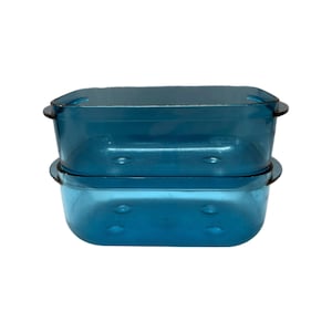 May include: Two rectangular, teal-colored glass baking dishes are stacked on top of each other. Each dish has a rounded rectangular shape with small handles on each side. The dishes are made of a transparent glass material.