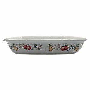 Könnte beinhalten: Rechteckige, weiße Keramik-Backform mit einem dekorativen Obst- und Blumenmuster. Das Muster umfasst rote Äpfel, gelbe Birnen und blaue Beeren. Die Form hat einen leicht gebogenen Rand und ist für den Ofen geeignet.