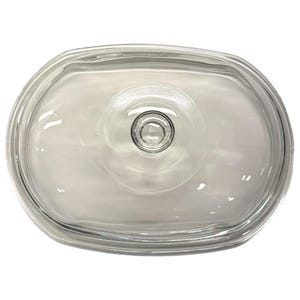 Puede incluir: Una tapa de vidrio transparente de forma ovalada con un asa circular en el centro. La tapa es transparente, lo que permite ver lo que cubre. El asa tiene un pequeño diseño circular en relieve. La tapa es probablemente para una fuente para hornear o utensilios de cocina similares.