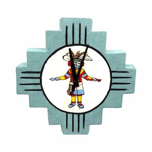 May include: A turquoise-colored clock with a Native American design. The clock face features a colorful figure with a feathered headdress. The clock has black hands and a unique, cross-shaped frame.