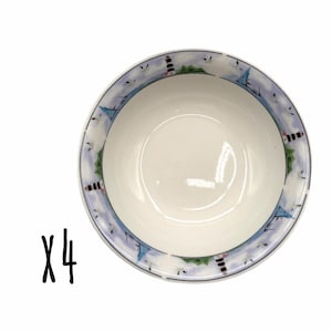 May include: A set of four white ceramic bowls featuring a decorative rim pattern of black and white lighthouses, blue sailboats, and small birds against a light blue sky background. The interior of each bowl is plain white with a smooth finish.