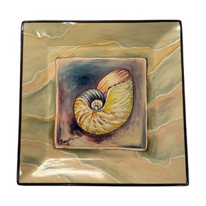 May include: Square decorative plate with a painted nautilus shell design. The plate features a square center with a nautilus shell in shades of yellow, blue, and brown. The outer border has a marbled effect in beige and green, with a black trim.