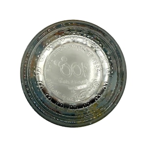 Puede incluir: Base de botella de vidrio transparente con texto en relieve y el n&uacute;mero 100 en el centro. El texto incluye las palabras "SPAN" y "14/23". La botella tiene forma circular y se ve desde abajo.