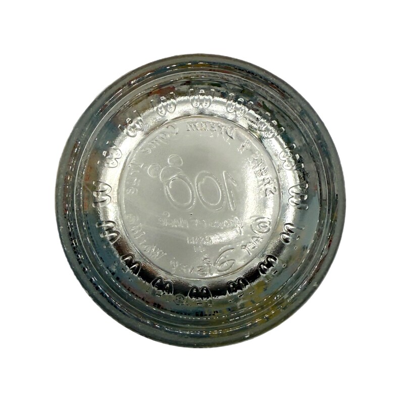 Puede incluir: Base de botella de vidrio transparente con texto en relieve y el n&uacute;mero 100 en el centro. El texto incluye las palabras "SPAN" y "14/23". La botella tiene forma circular y se ve desde abajo.