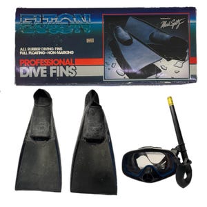 Könnte beinhalten: Ein Set aus schwarzen Tauchflossen, einem Schnorchel und einer Tauchmaske. Die Flossen sind mit "Volt" gekennzeichnet. Auf der Box steht "Professional Dive Fins" und "All Rubber Diving Fins". Die Maske hat eine blaue Umrandung. Der Schnorchel hat ein gelbes Mundstück.