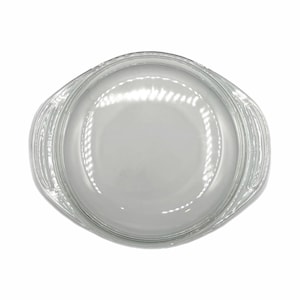 May include: A clear glass baking dish with a rounded oval shape and two handles. The dish is empty and appears to be new. The glass is transparent, allowing the contents to be seen.