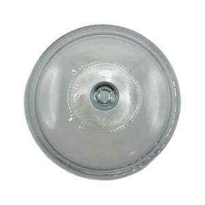 Puede incluir: Una cúpula de pastel de vidrio transparente con un diseño circular. La cúpula tiene una parte superior redondeada y una superficie ligeramente texturizada. El centro presenta un patrón detallado en forma de estrella. El diseño general es simple y elegante.