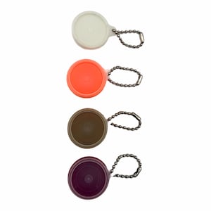 May include: Four round, colorful bottle stoppers with attached ball chains. The stoppers are white, orange, brown, and purple. The stoppers are made of plastic and are designed to fit snugly into the neck of a bottle.