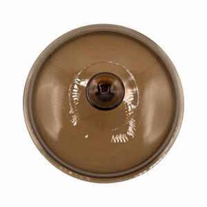 Puede incluir: Vista superior de un objeto de vidrio marrón con base circular y tallo. El objeto tiene un acabado brillante y un centro marrón oscuro. El borde de la base es de un tono más claro de marrón.