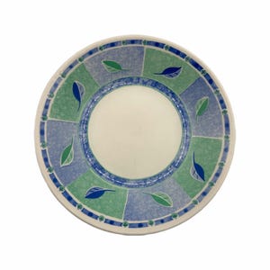 Könnte beinhalten: Runder Keramikteller mit cremefarbenem Mittelteil und dekorativem Rand. Der Rand weist abwechselnd blaue und grüne Quadrate, blaue und grüne Blätter sowie einen blau-grünen gepunkteten Rand auf.