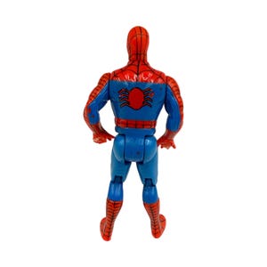 May include: A vintage Spider-Man action figure, viewed from the back. The figure is primarily blue and red, with a spider emblem on the back. The figure's design includes web patterns and a classic superhero aesthetic.