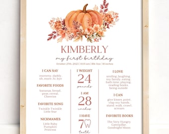 May include: A watercolor illustration of a pumpkin with fall leaves and a chart listing a baby's first birthday milestones. The chart includes the baby's name, Kimberly, weight (24 pounds), height (28 inches), favorite foods, songs, books, and other details.