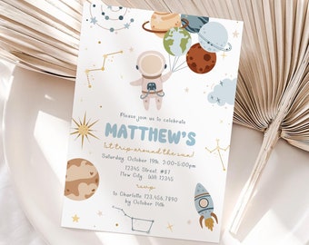 May include: A white invitation card with a blue and yellow astronaut holding balloons shaped like planets. The text on the card reads "Please join us to celebrate Matthew's 1st trip around the sun! Saturday October 19th, 2:00-5:00pm 12345 Street #87 New City WA 12345 RSVP To Charlotte 123.456.7890 by October 14th"