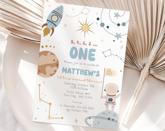 May include: A blue and white space-themed first birthday party invitation with a rocket, planets, stars, and an astronaut. The invitation says "5, 4, 3, 2... One" and "Please join us to celebrate Matthew's 1st trip around the sun!" with the date, time, and RSVP information.