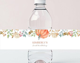 May include: Water bottle label with a watercolor design of fall leaves, berries, and a pumpkin. The text on the label reads "Kimberly's first birthday".